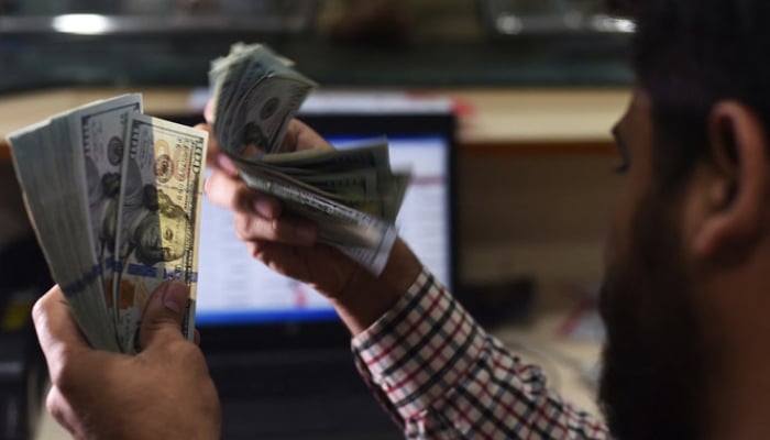 627086_9262288_updates A Pakistani dealer counts US dollars at a currency exchange shop in Karachi. — AFP/File